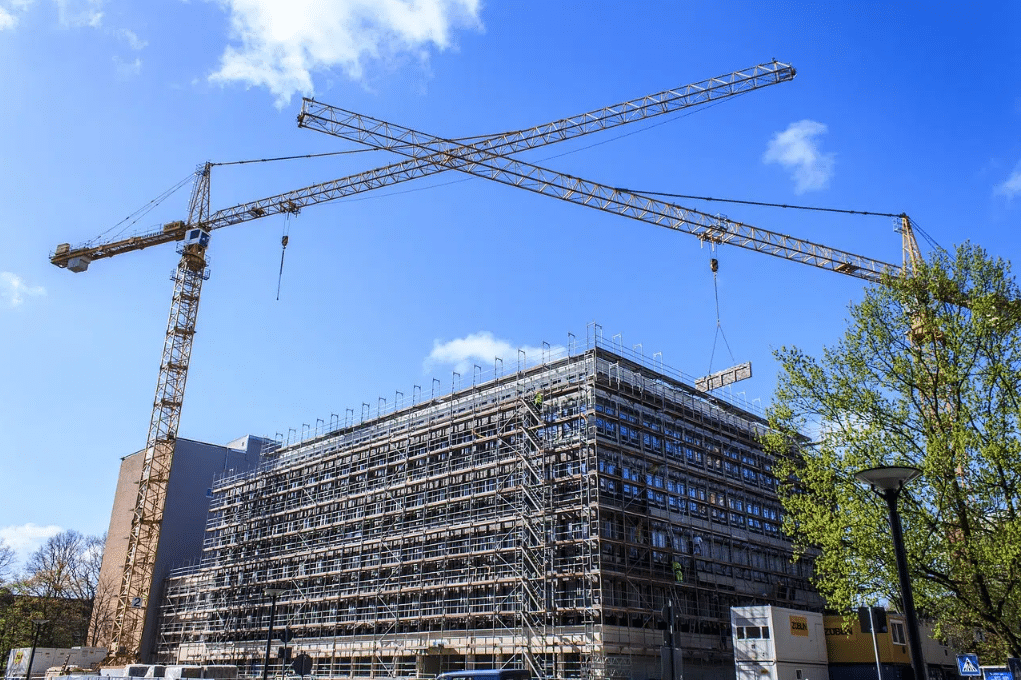 Large apartment building construction in progress with 2 cranes in front