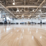 Empty indoor sports arena with polished wooden floor and high ceiling