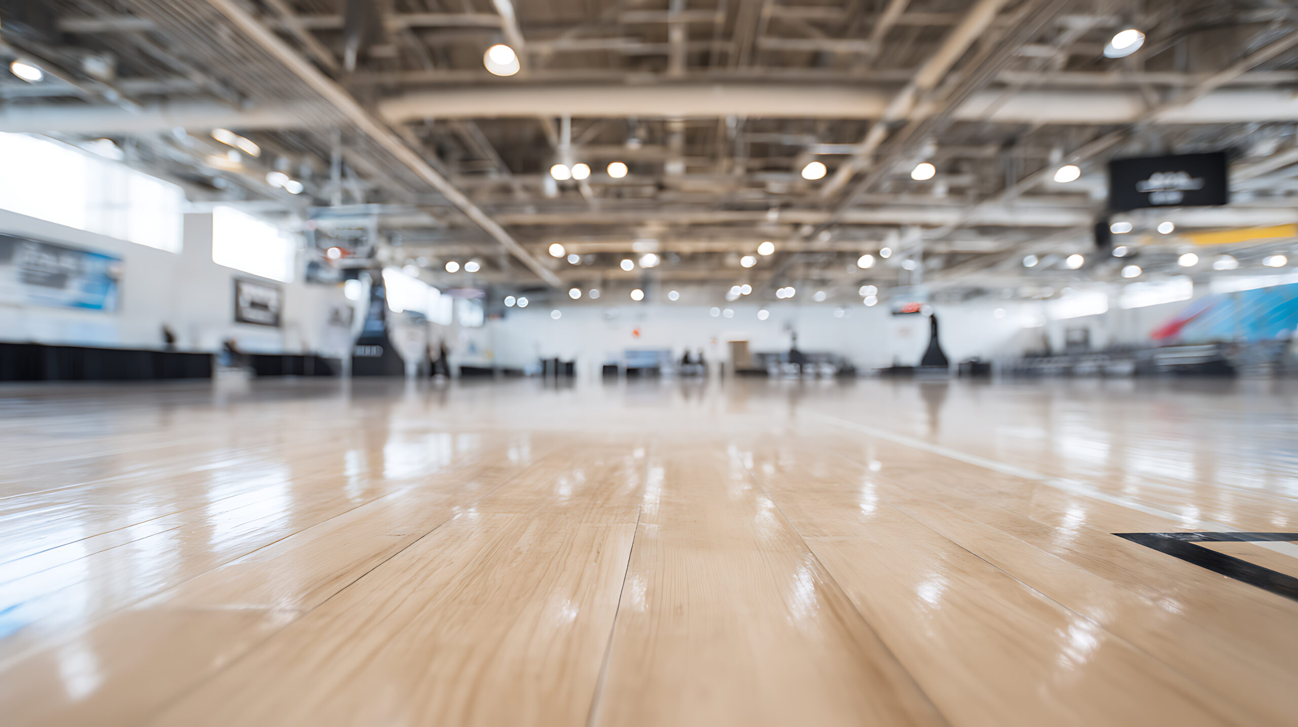 Empty indoor sports arena with polished wooden floor and high ceiling
