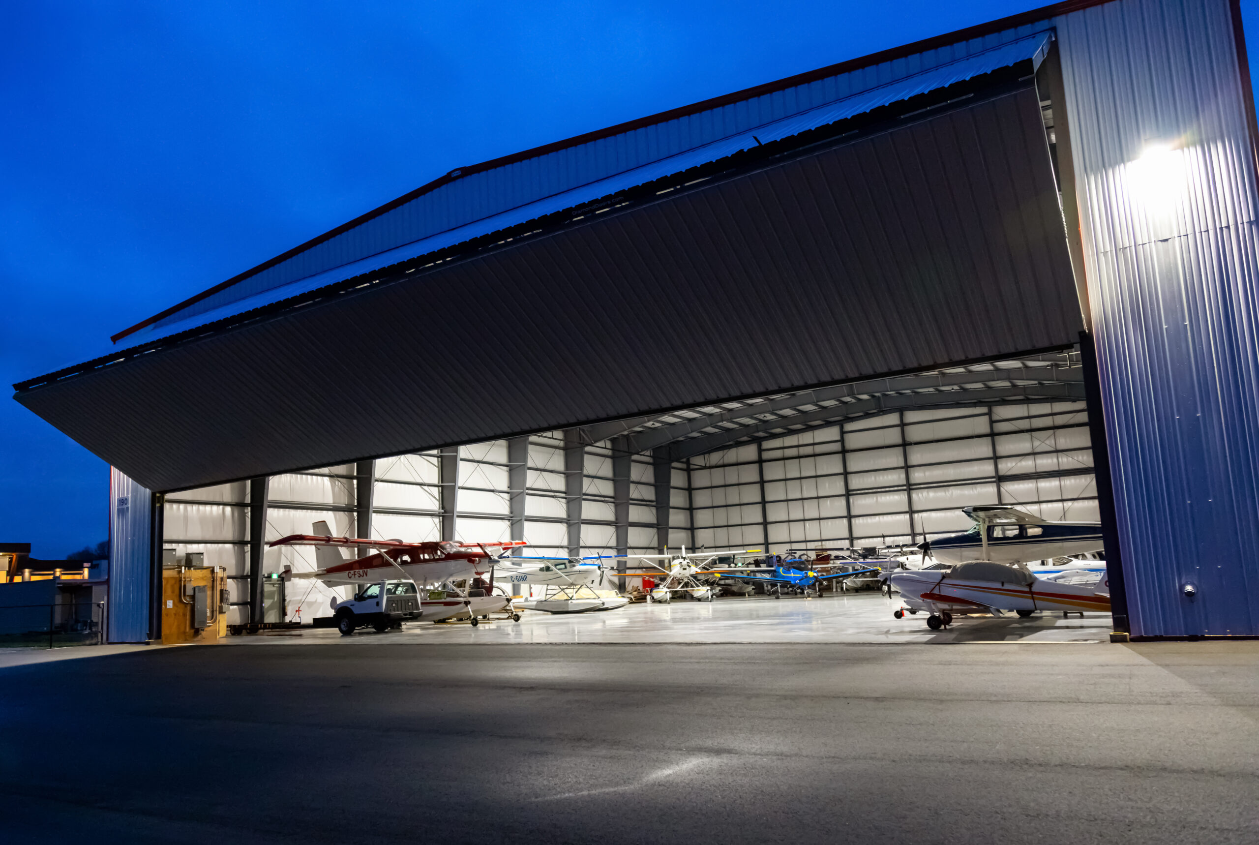 Airplanes parked inside a hanger with a door open at an Airport