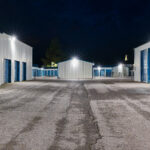 Evening view of a large illuminated self storage facility offering individual units for rent.