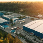 Aerial view of warehouse storages or industrial factory or logistics center from above. Aerial view of industrial buildings and equipment machines at sunset