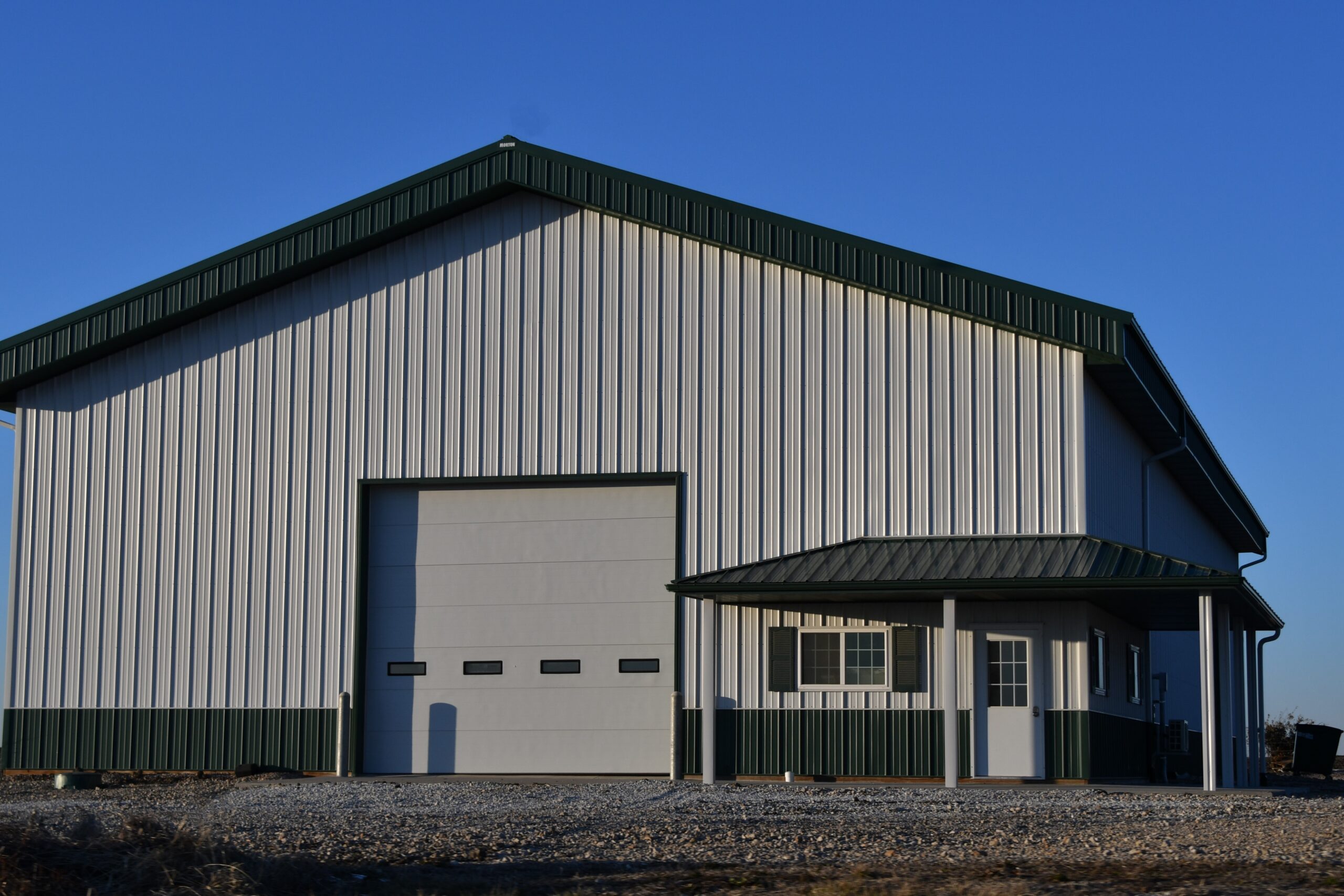 Metal white and green shop building with large garage door