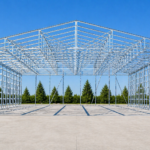 Front view of a tube steel building frame with galvanized hollow structural sections, set on a concrete slab with a clean, open background and clear blue sky.