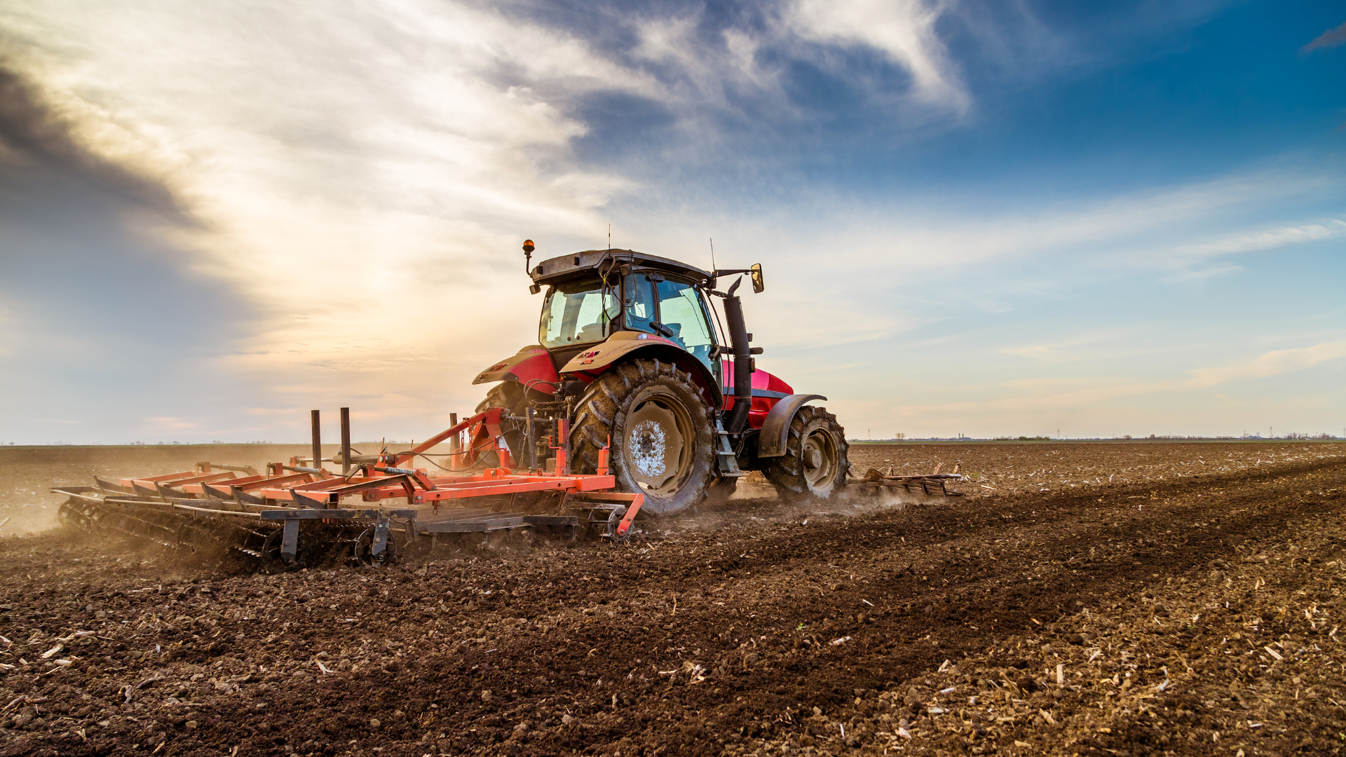 Farm machinery tractor preparing soil in open field for planting