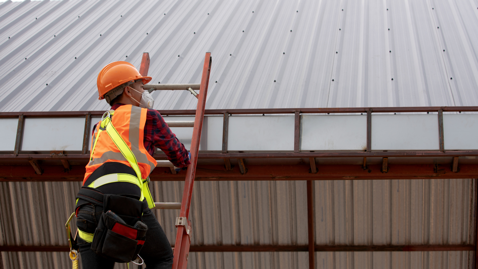 Construction worker installing or inspecting a standing seam metal roof system on a steel building, demonstrating commercial metal roofing installation and long-term roof performance.