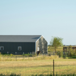 Metal farm storage building on rural property with fenced pasture