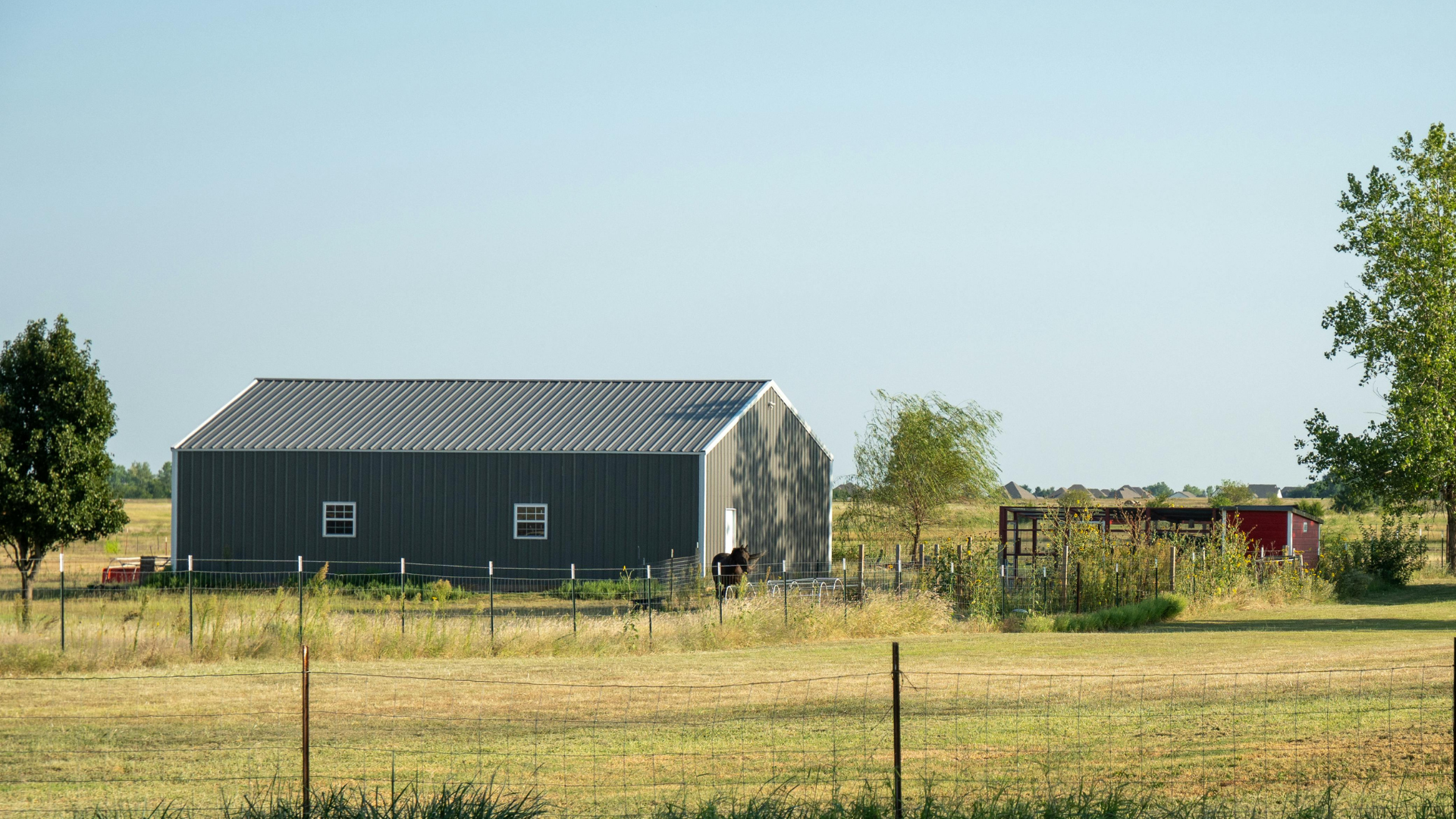 Metal farm storage building on rural property with fenced pasture