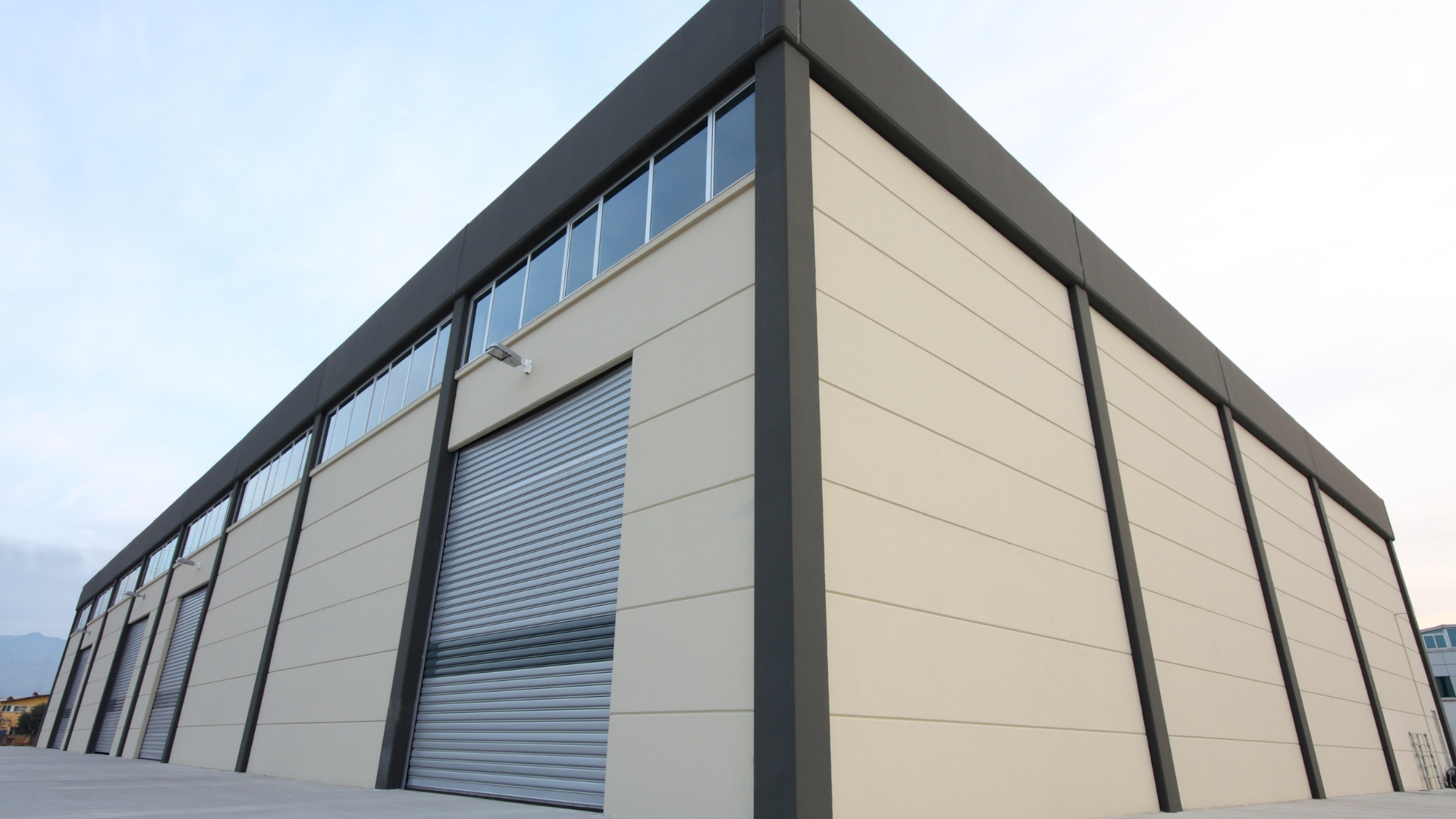 Exterior of a modern flex industrial building with high-bay warehouse space, office windows, and overhead loading door for flexible business operations.