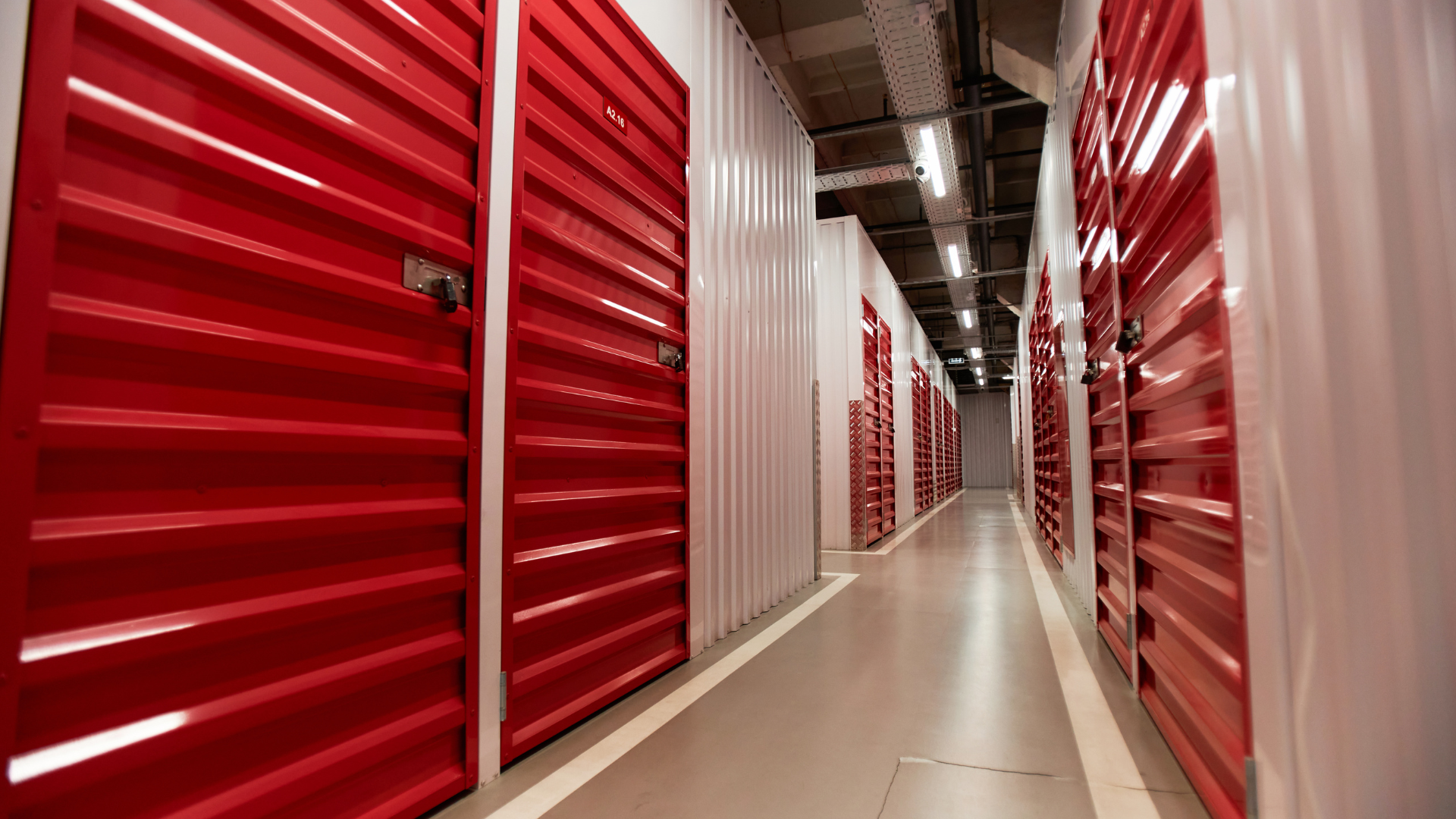 Interior hallway of a modern self-storage facility featuring secure roll-up storage unit doors and wide access aisles.
