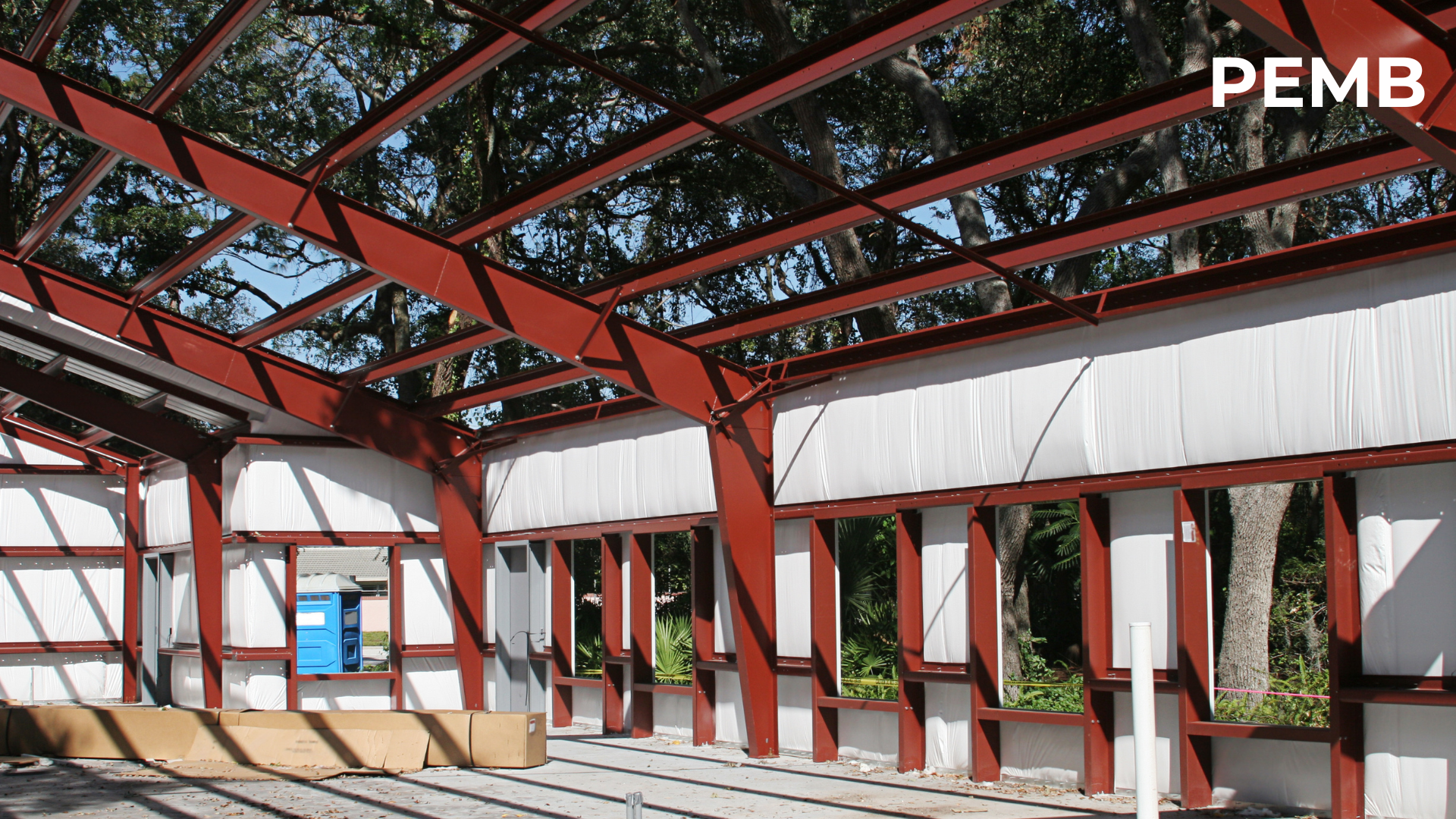 Interior view of a pre-engineered metal building frame under construction, showing rigid steel rafters and wide clear-span space. PEMB systems provide a proven, cost-effective solution for low-rise commercial and industrial buildings with fast erection and efficient structural performance.