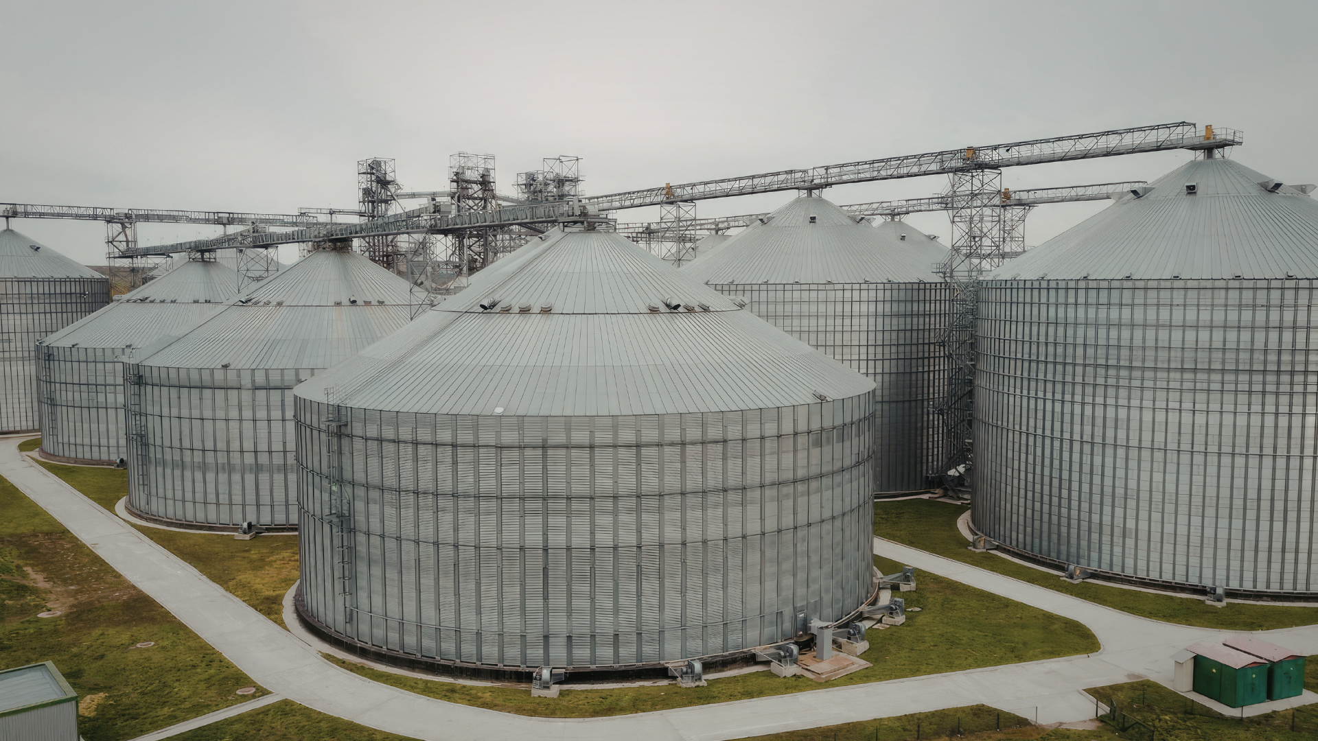 Large commercial grain storage silos connected by overhead conveyors at an agricultural grain handling facility.