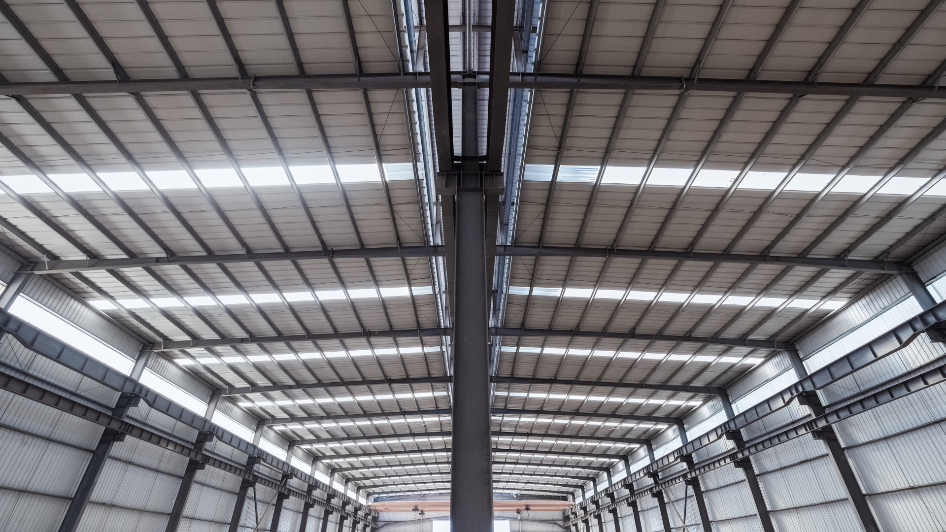 Interior of a steel frame warehouse featuring exposed structural beams, high ceilings, and natural daylight panels.