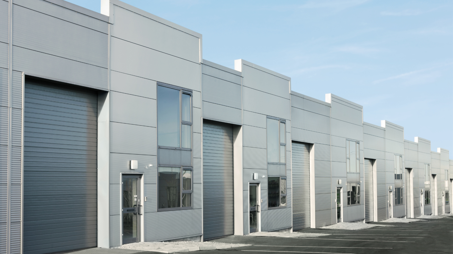 Modern flex industrial building with multiple storefront warehouse units featuring overhead doors, offices, and adaptable commercial space.
