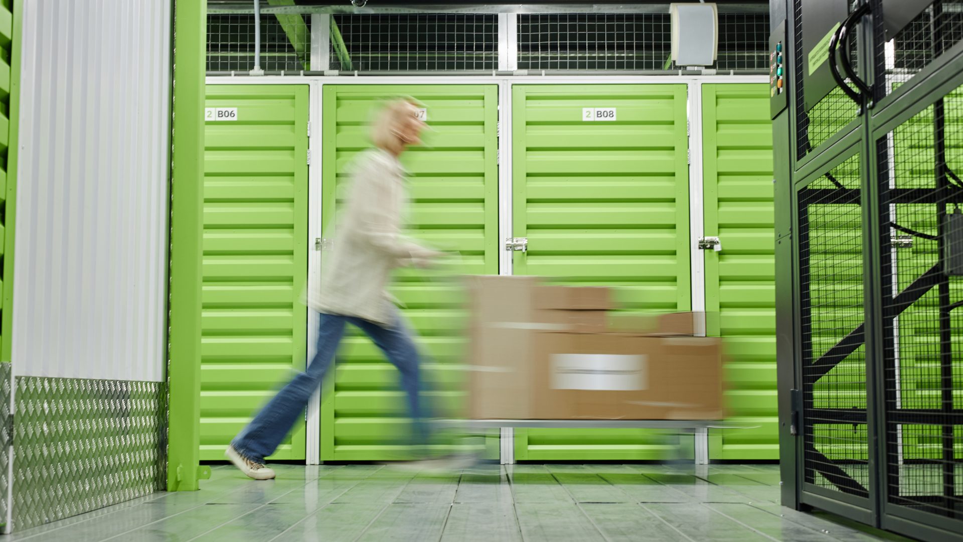 Customer transporting boxes through a modern indoor self-storage facility with secure climate-controlled storage units.