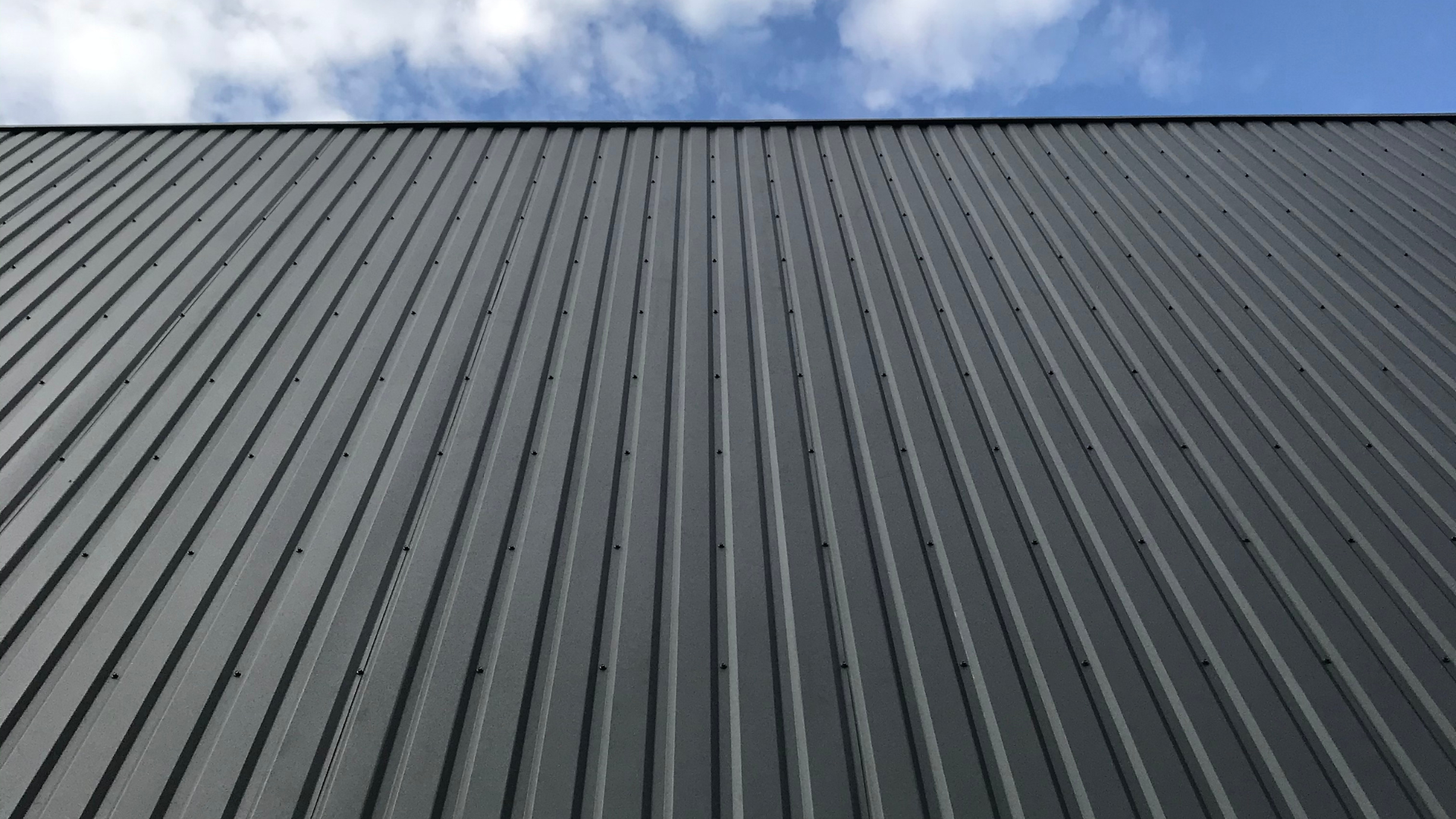 Close-up view of ribbed metal wall panels installed on a commercial steel building. Metal panel systems offer durability, weather resistance, low maintenance, and long-term performance for industrial facilities.