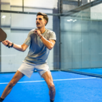 Player on an indoor pickleball court with proper lighting and court enclosure.